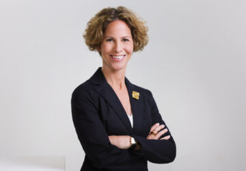 Professionelles Business-Porträt einer lächelnden Frau im dunklen Blazer vor hellem Hintergrund – Führung, Beratung, Personalbranding.